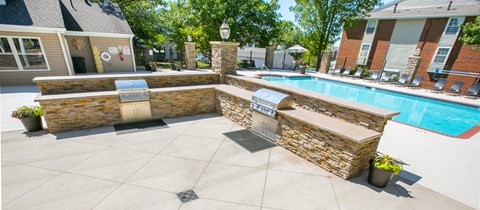 a swimming pool with a privacy wall and a bar area in front of a house
