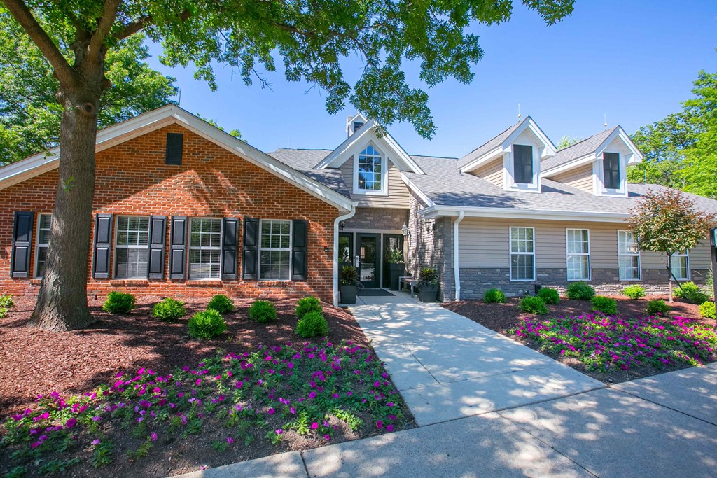 the front of a house with a sidewalk and a tree