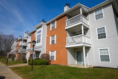 an apartment building with brick and white siding and a balcony