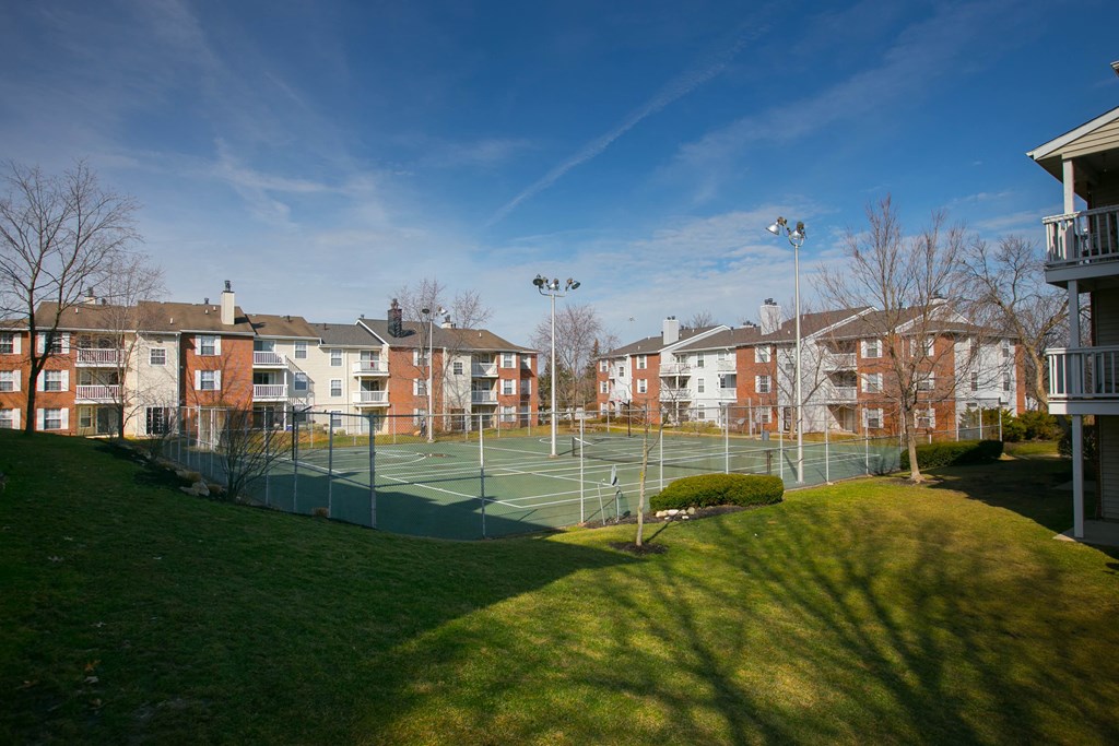 a tennis court with apartments in the background