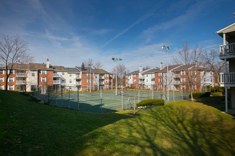 a tennis court with apartments in the background