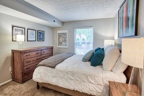 a bedroom with a bed and a dresser and a window