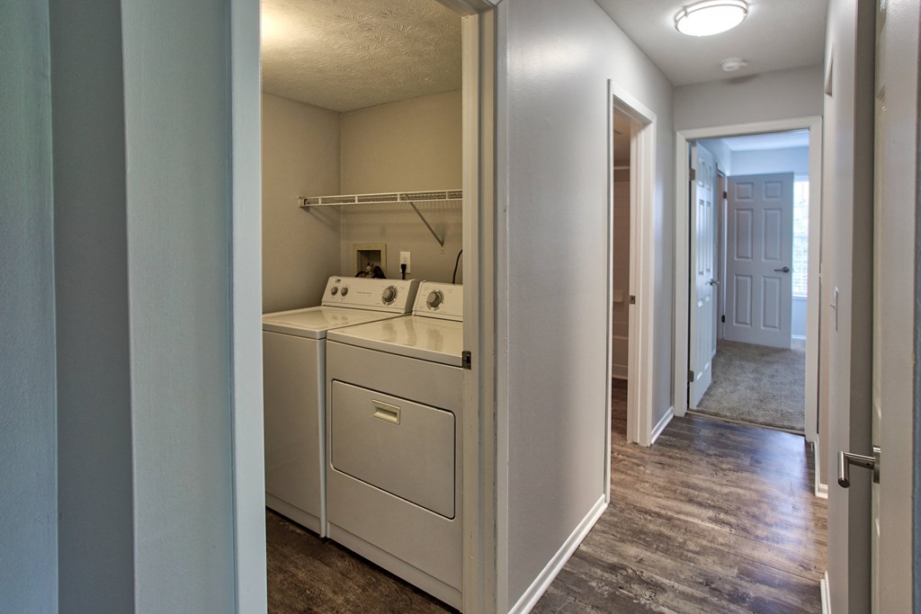 a laundry room with a washer and dryer and a hallway with a door
