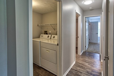 a laundry room with a washer and dryer and a hallway with a door
