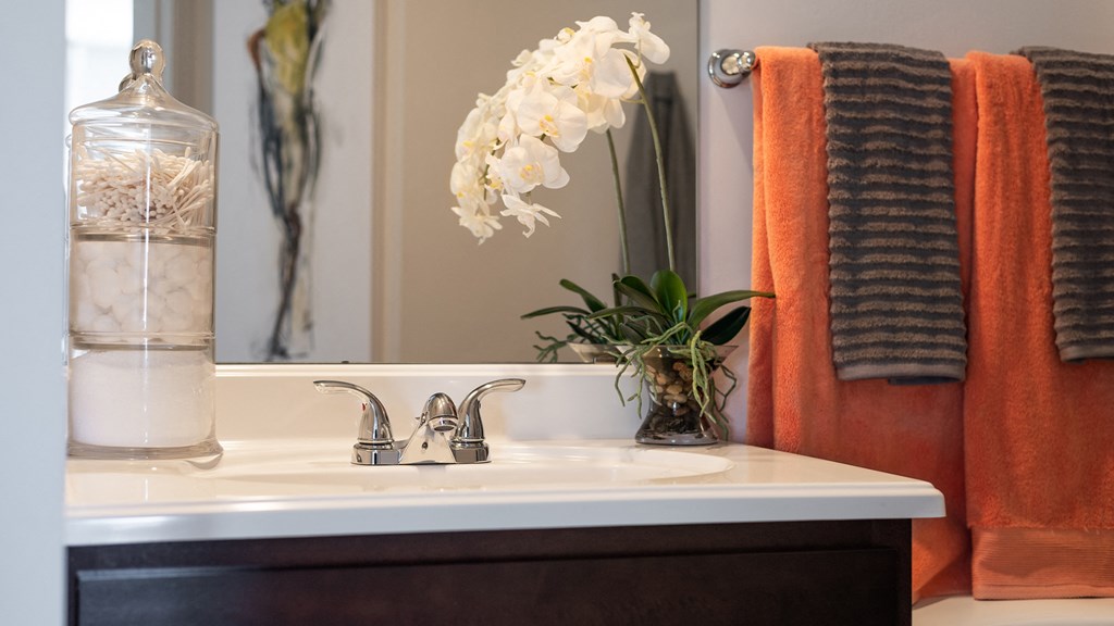 a bathroom with a sink and a mirror and orange towels