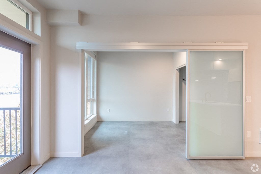 an empty living room with white walls and a sliding glass door