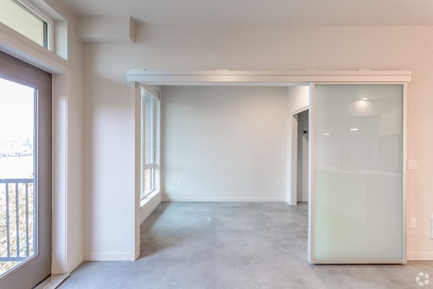 an empty living room with white walls and a sliding glass door