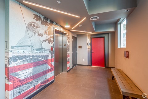 a hallway with a red door and a mural of a bird on the wall next