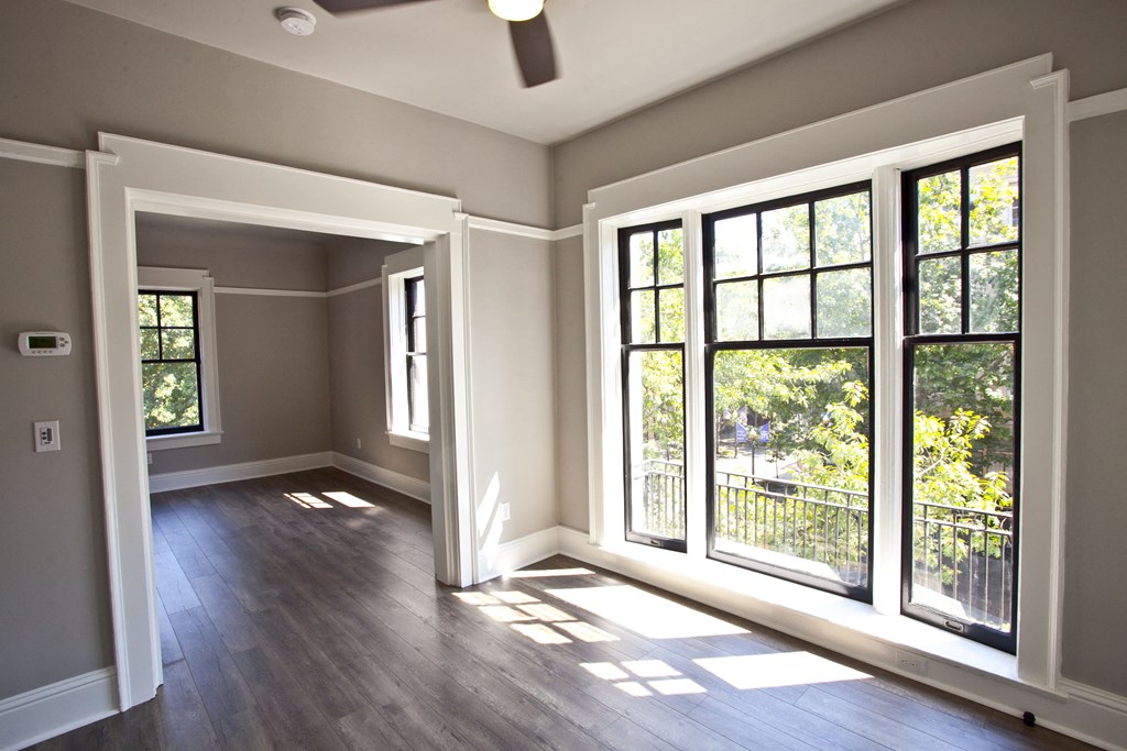 an empty living room with large windows and wood floors