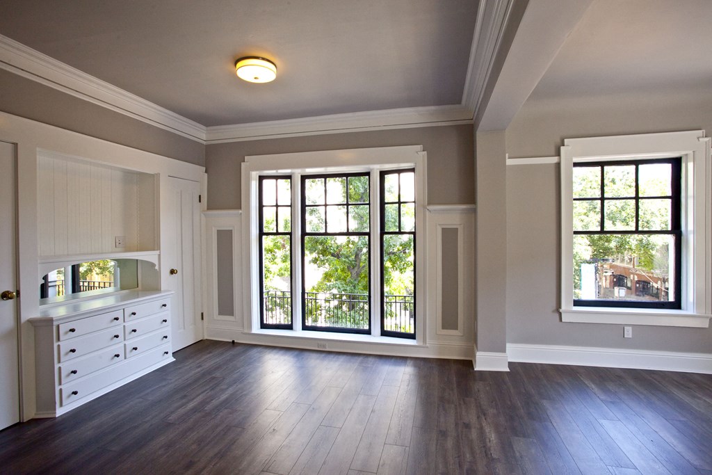 an empty living room with large windows and wood flooring