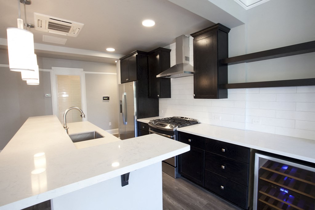 a kitchen with black cabinets and white counter tops and a sink