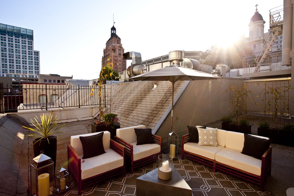 a rooftop terrace with couches and chairs and a city in the background