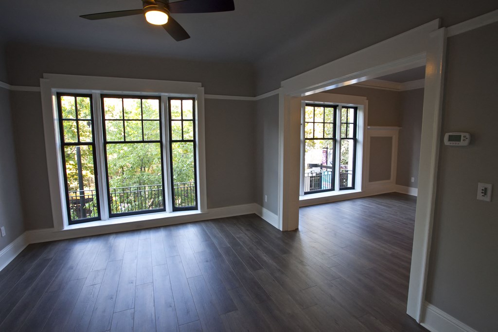 an empty living room with wood floors and large windows