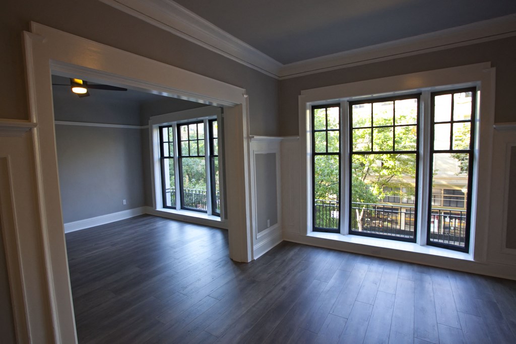 an empty living room with wood floors and large windows