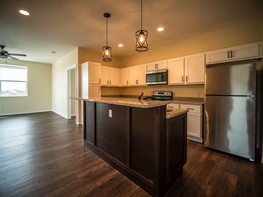 a kitchen with a center island and a stainless steel refrigerator