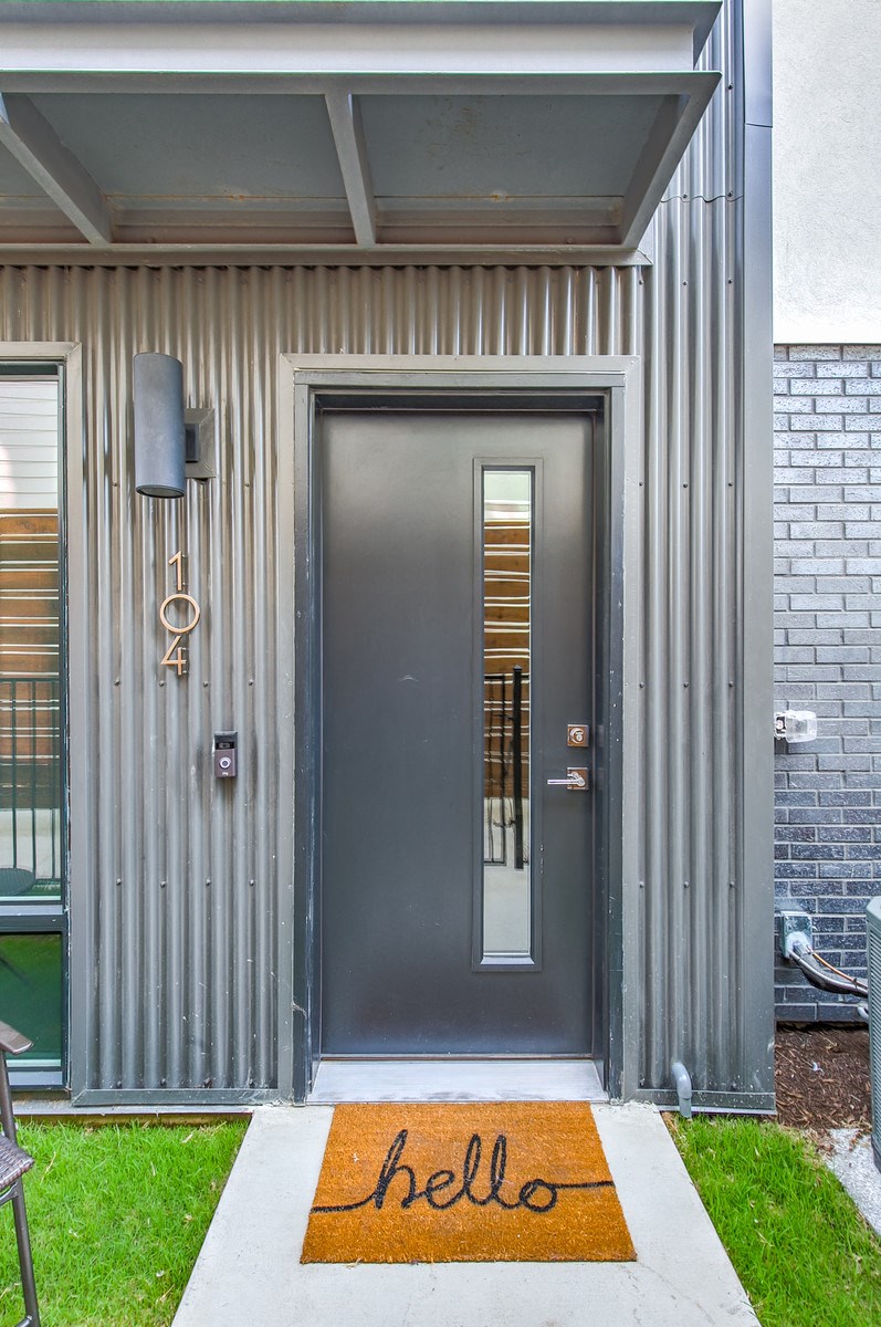 the front door of a home with a hello rug on the sidewalk