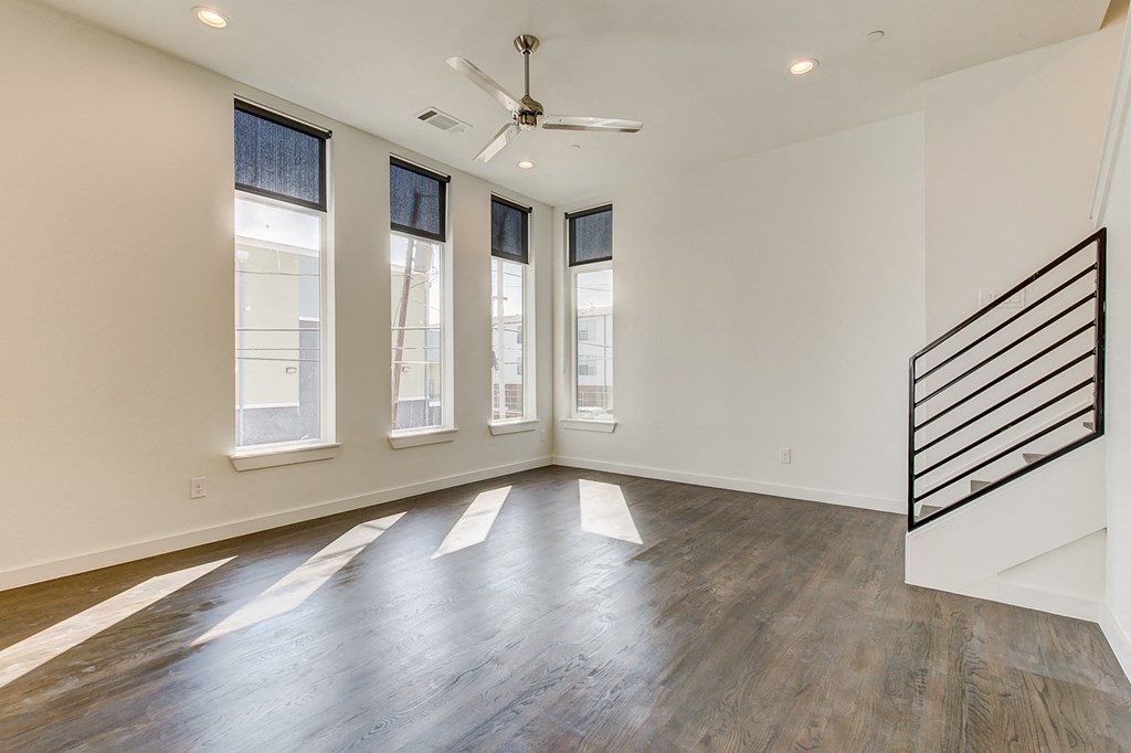 an empty living room with a ceiling fan and windows