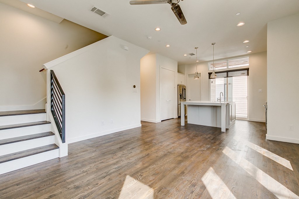 an empty living room with a staircase and a kitchen