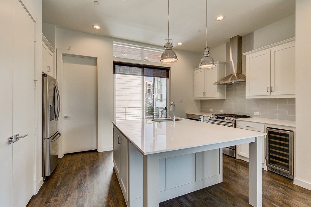 a white kitchen with a large island and a stainless steel refrigerator