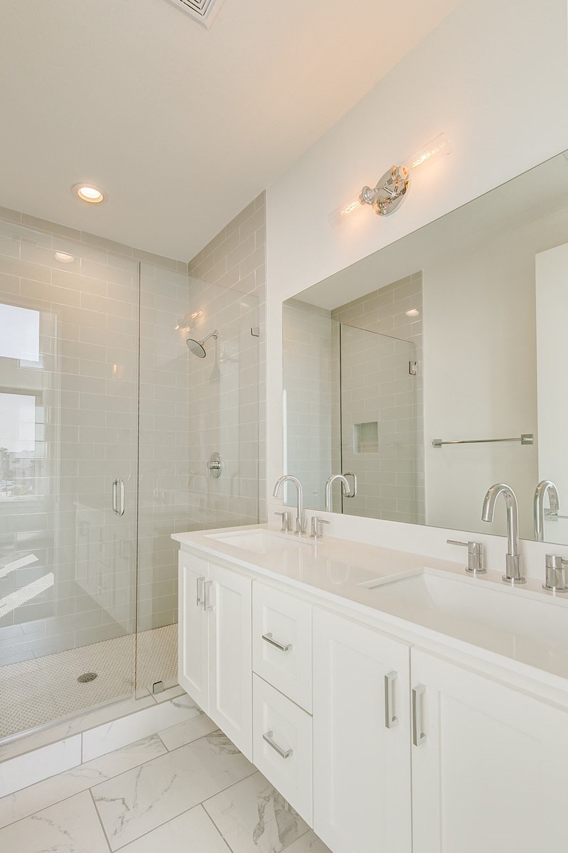 a white bathroom with two sinks and a shower