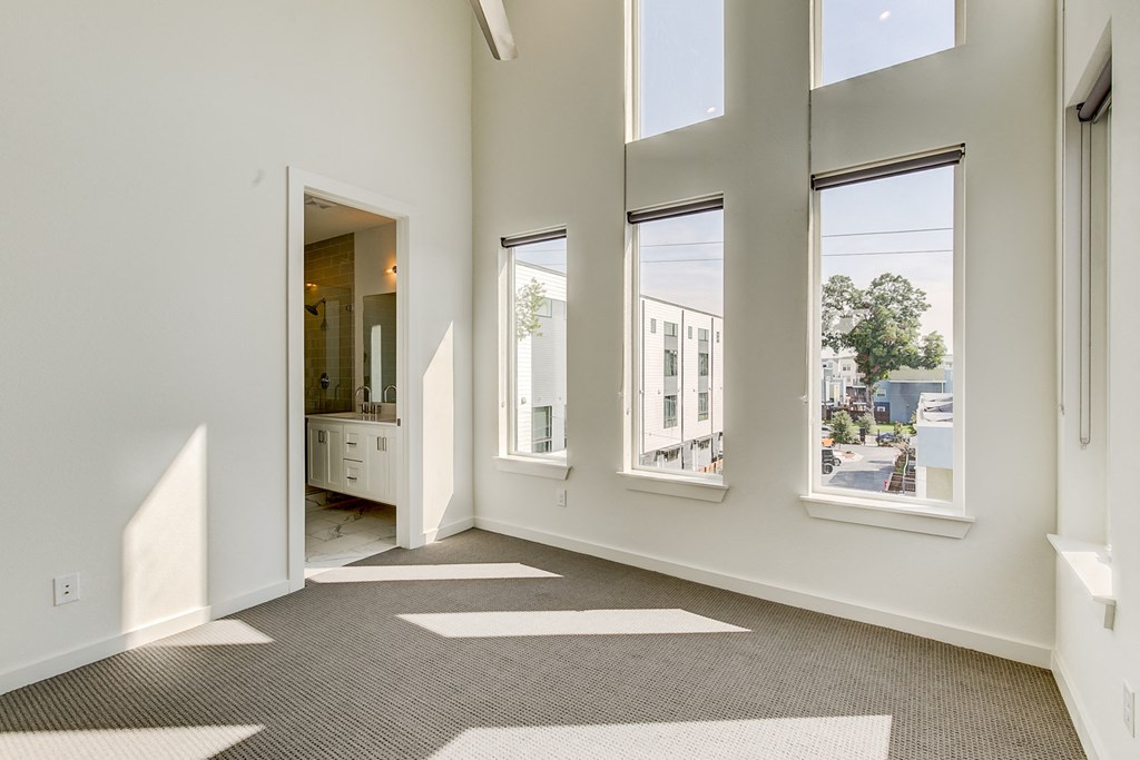an empty living room with large windows and a bathroom