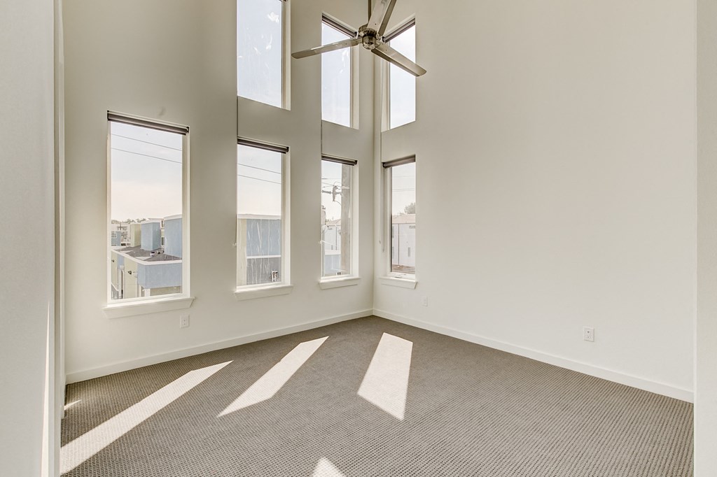 an empty living room with windows and a ceiling fan