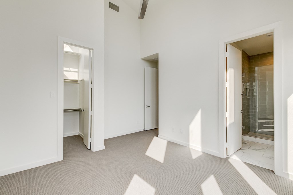a renovated living room with white walls and a bathroom with a glass shower