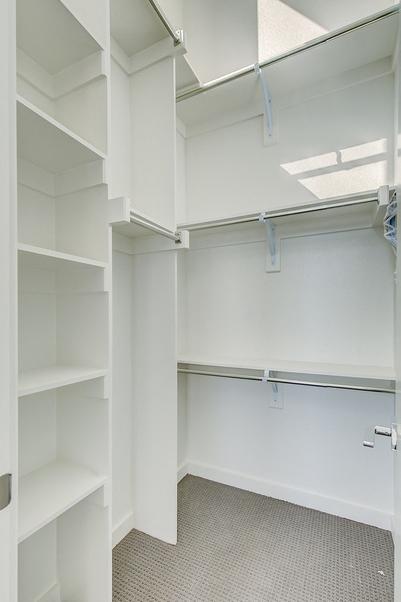 a walk in closet with white shelves and a door