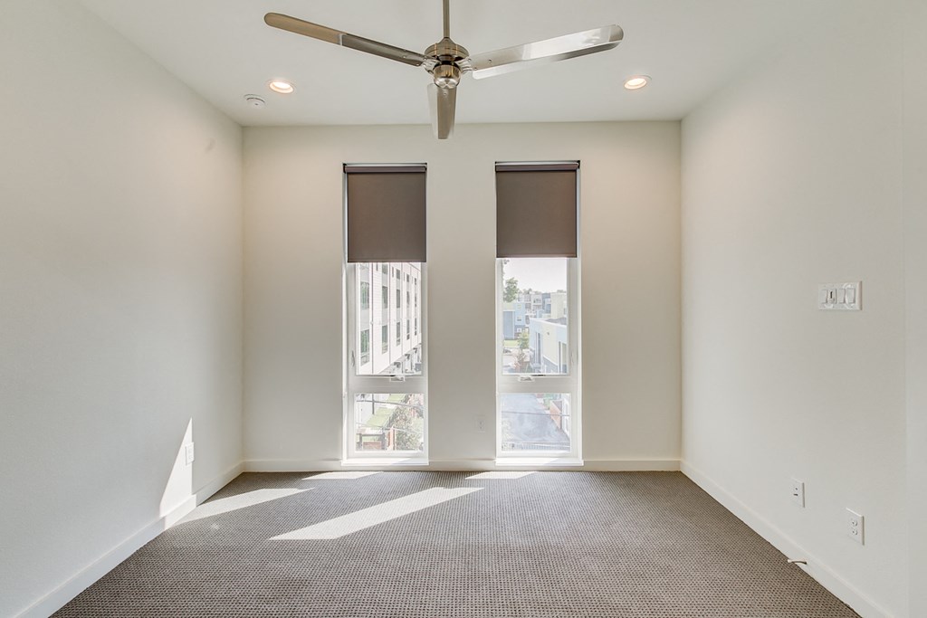 an empty room with windows and a ceiling fan