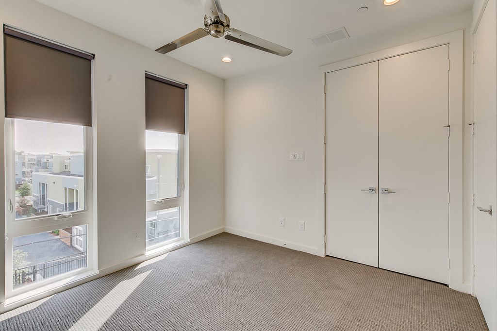 an empty living room with a ceiling fan and window
