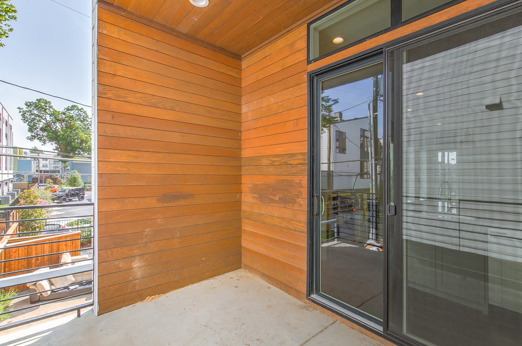 the entrance to the home has a glass door and a patio