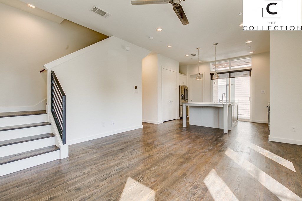 a kitchen and living room with white walls and wood floors