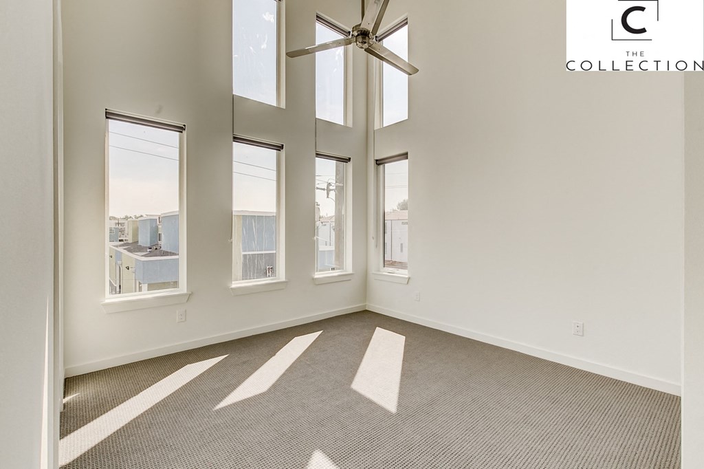 an empty living room with windows and a ceiling fan