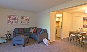 a living room with a couch and a chair and a dining room and a kitchen