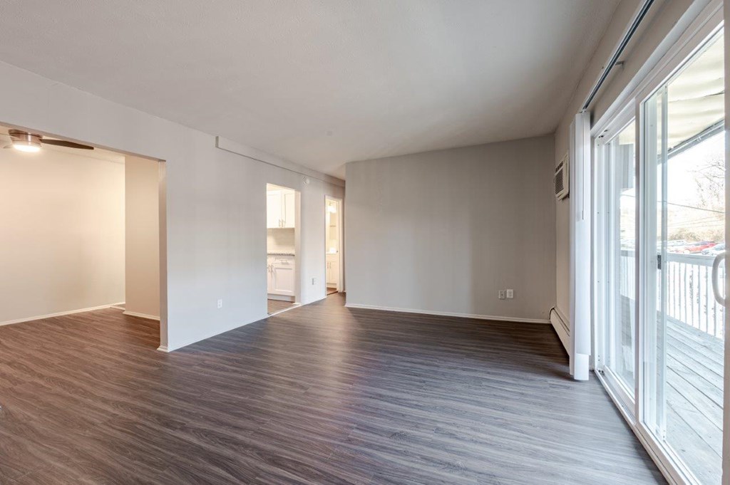 A spacious room with wooden flooring and white walls.