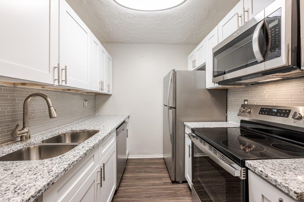 A kitchen with a refrigerator, sink, and stove.