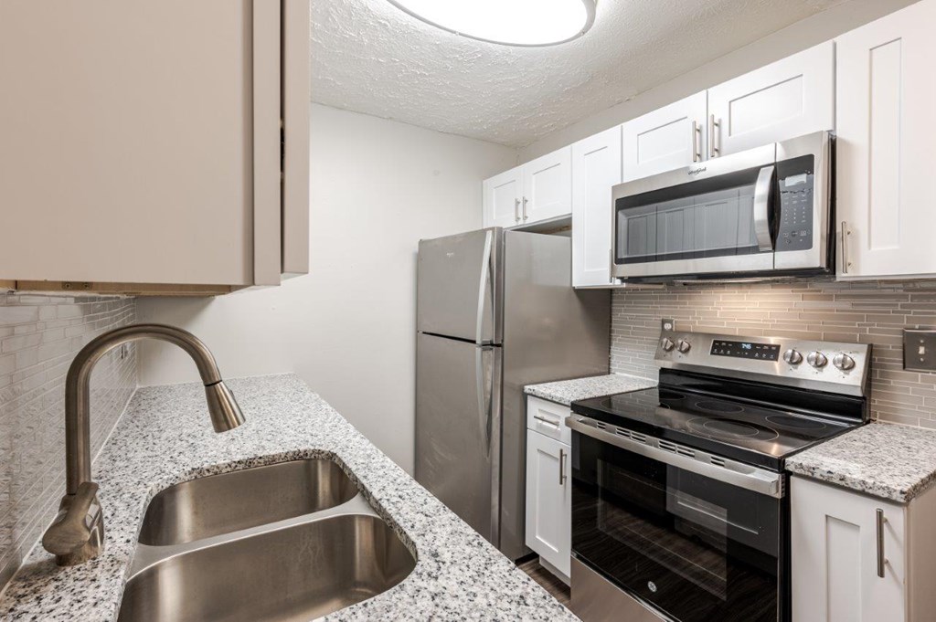A kitchen with a stainless steel refrigerator, oven, and microwave.