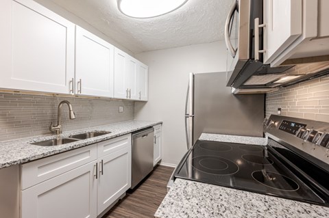 A kitchen with white cabinets and a black stove top oven.