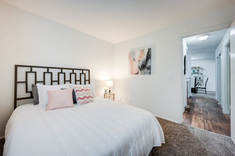 A bedroom with a large bed and a painting on the wall.