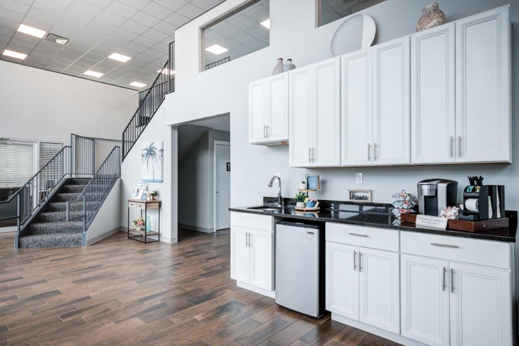 A kitchen with white cabinets and a staircase.