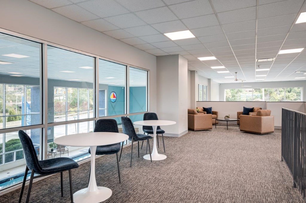 A room with a white table and black chairs.