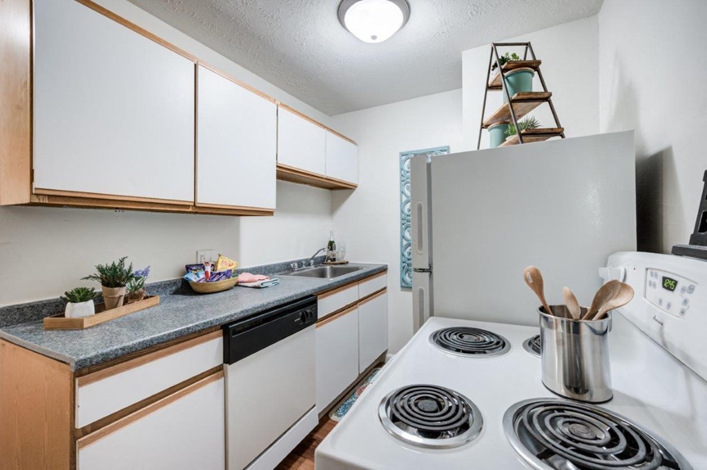 A kitchen with a white stove top oven and white cabinets.