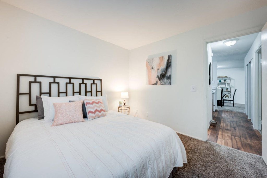 A bedroom with a large bed and a painting on the wall.