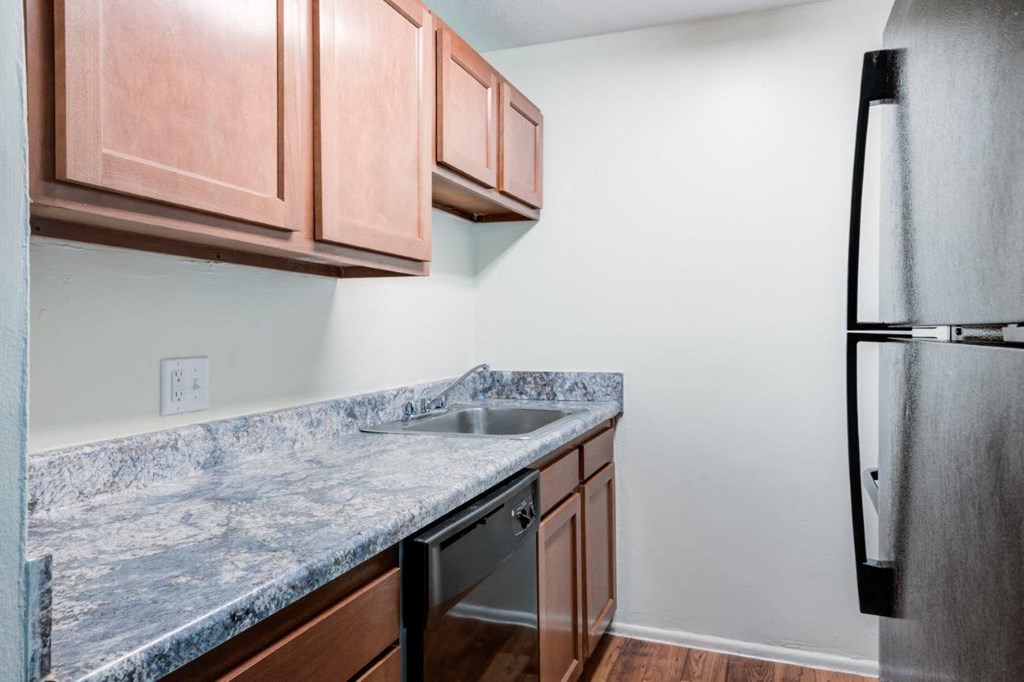 A kitchen with a granite countertop and wooden cabinets.