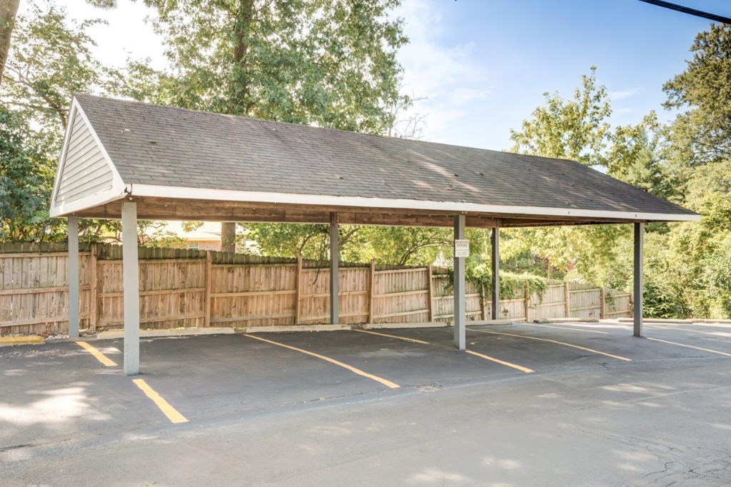 A covered parking area with a wooden fence in the background.