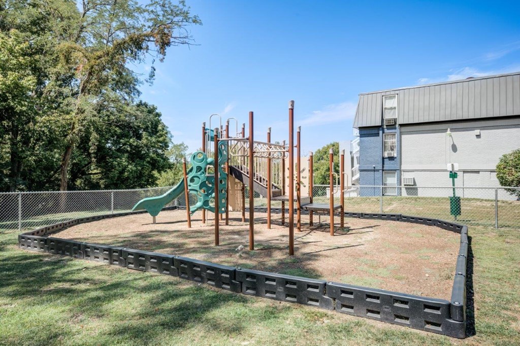 A playground with a green slide and a wooden structure.