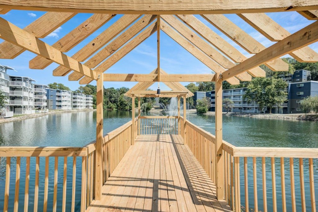 A wooden deck overlooks a body of water with buildings in the background.