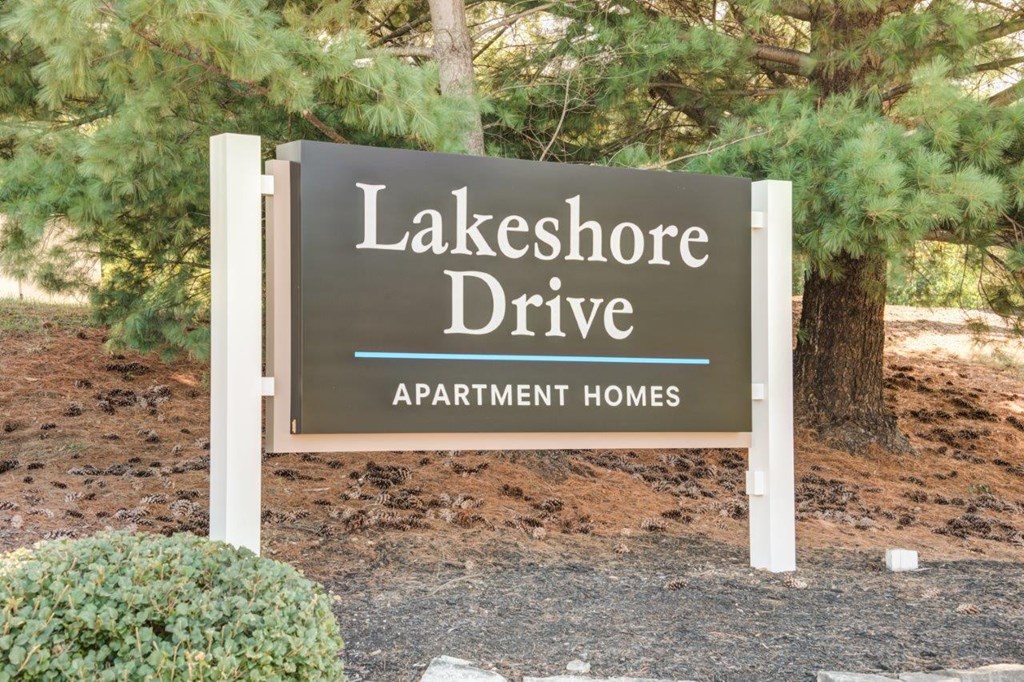 A sign for Lakeshore Drive apartment homes stands in front of a tree.