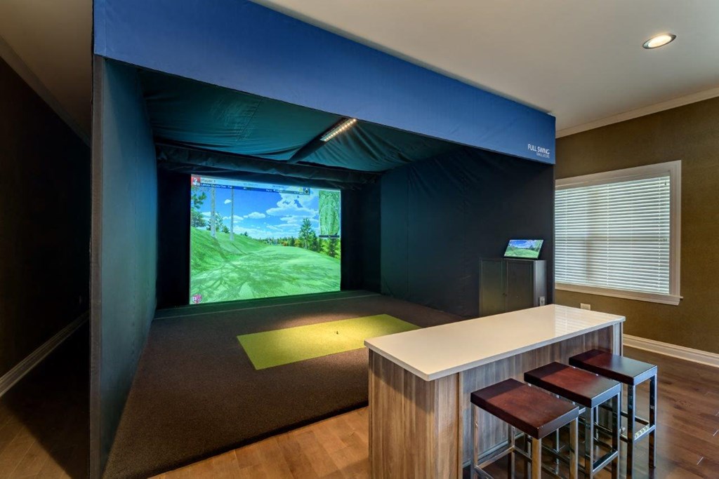 a room with a simulator and a bar with three stools