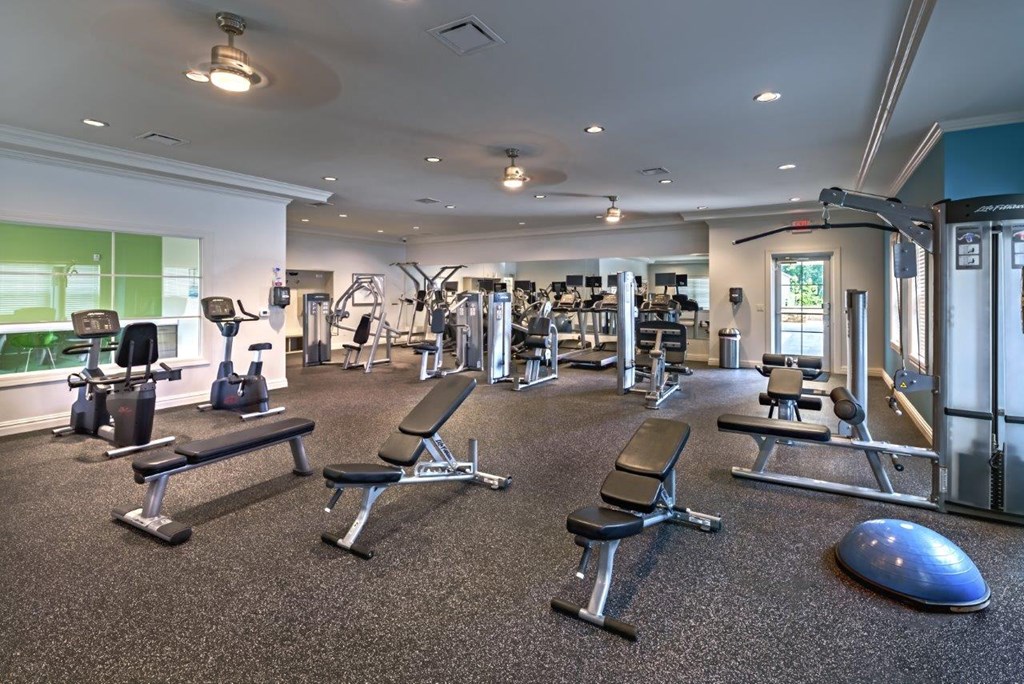a gym with weights and cardio equipment on the floor and a window